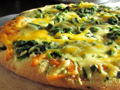 Homemade cheesy spinach pizza with an egg on top